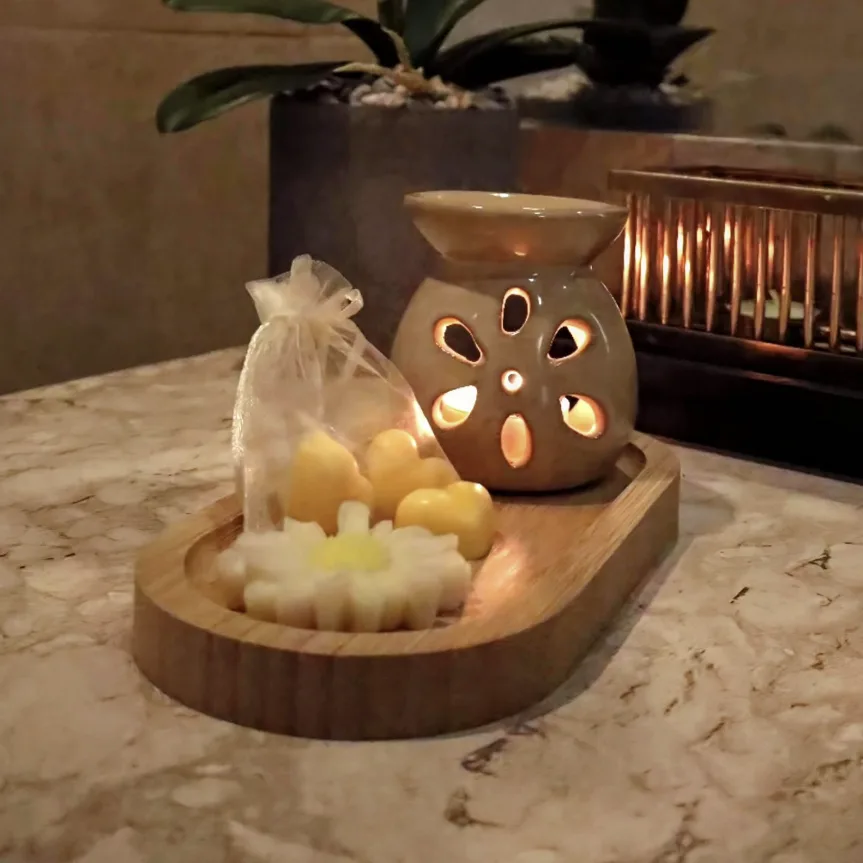 Hornito de cerámica encendido junto a wax melts sobre bandeja de madera