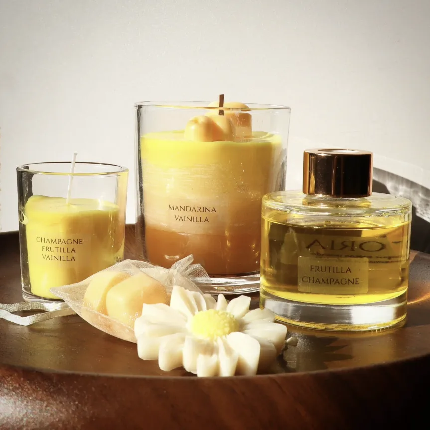 Velas Evoria Mandarina Vainilla y Champagne Frutilla Vainilla junto a un difusor Frutilla Champagne sobre bandeja de madera